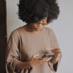 woman in brown long sleeve shirt holding smartphone